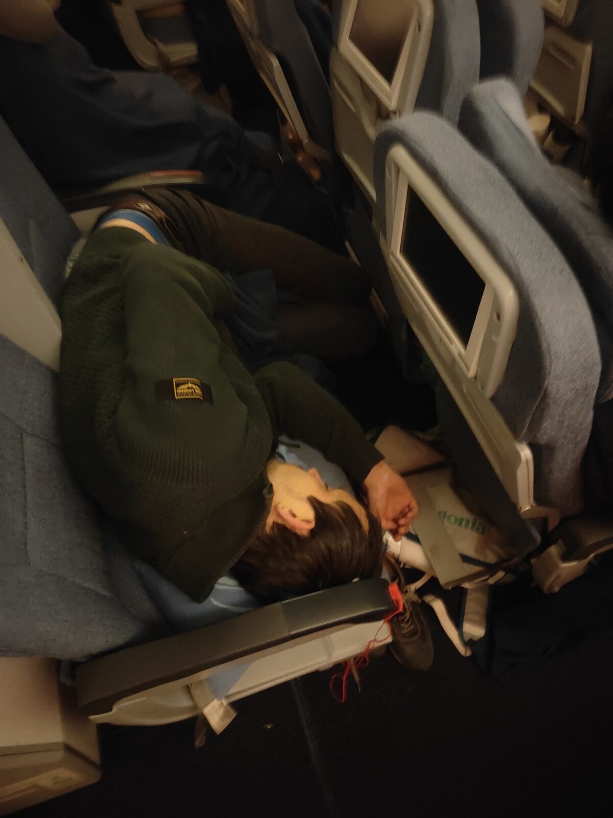 Teilnehmer schläft quer über die Sitze im Nachtflug