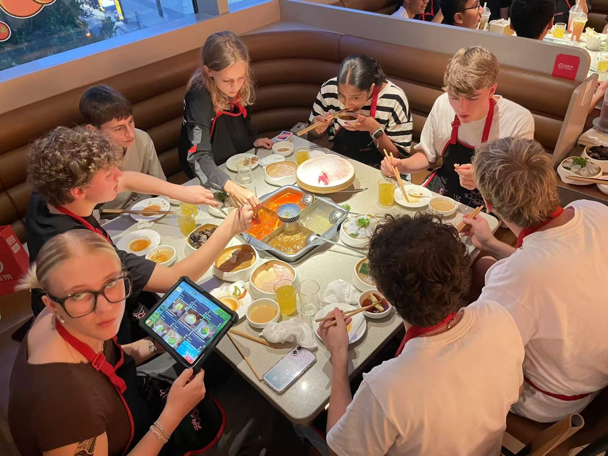 Gruppe beim Hotpot mit roten Schürzen